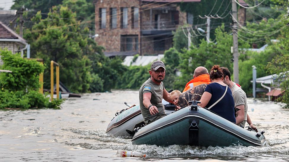 People use a rubber boat in a flooded street of Kherson, Ukraine, 07 June 2023