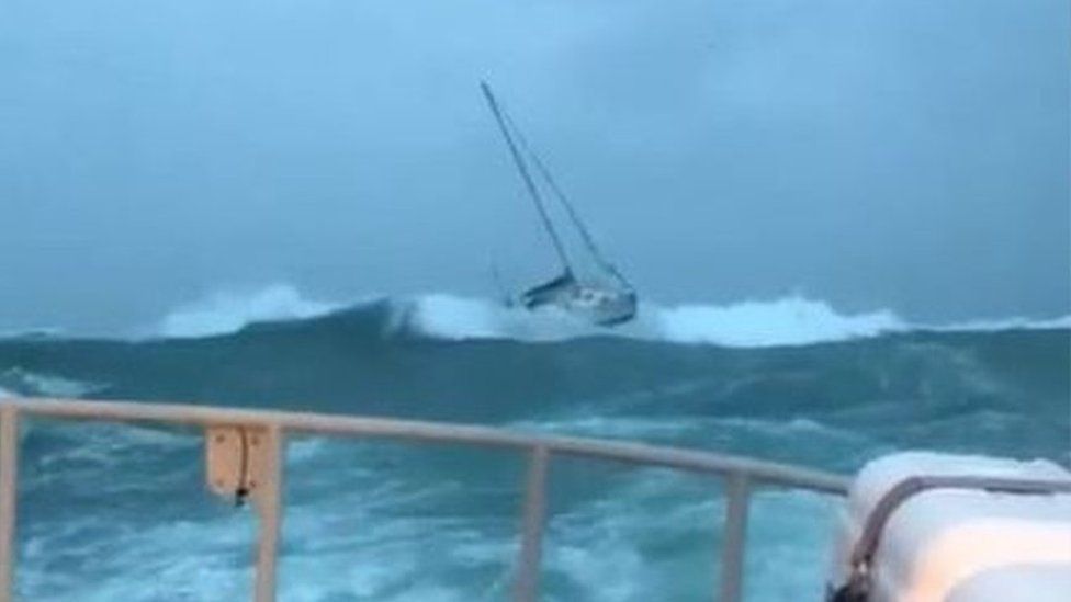 Yacht being towed by lifeboat in rough seas