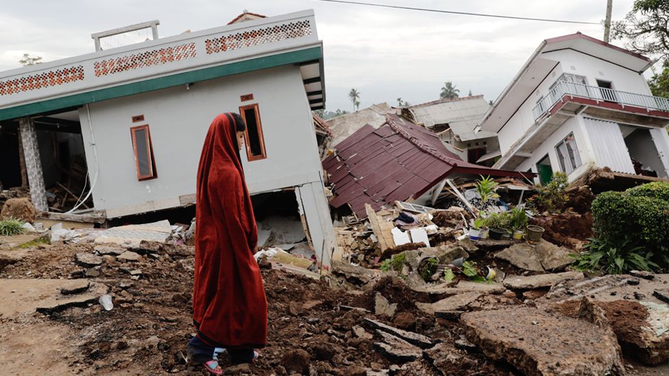 นักเรียนโรงเรียนแห่งหนึ่งมองดูโรงเรียนประจำอิสลามที่พังถล่มเมื่อวันที่ 23 พฤศจิกายน พ.ศ. 2565 หลังจากเกิดแผ่นดินไหวในเมือง Cianjur ประเทศอินโดนีเซีย