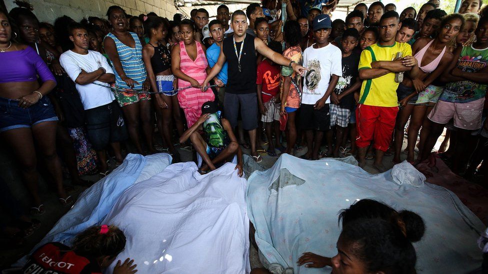 A group of people gather in front of dead bodies as Police intensified an operation against drug trafficking after the falling of a helicopter that left four agents dead, at shanty town Cidade de Deus, in Rio de Janeiro, Brazil, 20 November 2016.