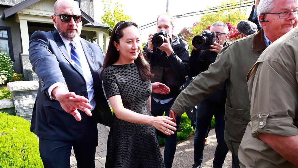 Meng Wanzhou is escorted b y security as she leaves her home on May 2019 in Vancouver