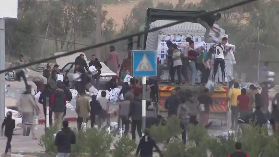 Men on the back of an aid lorry throw boxes down onto crowds below