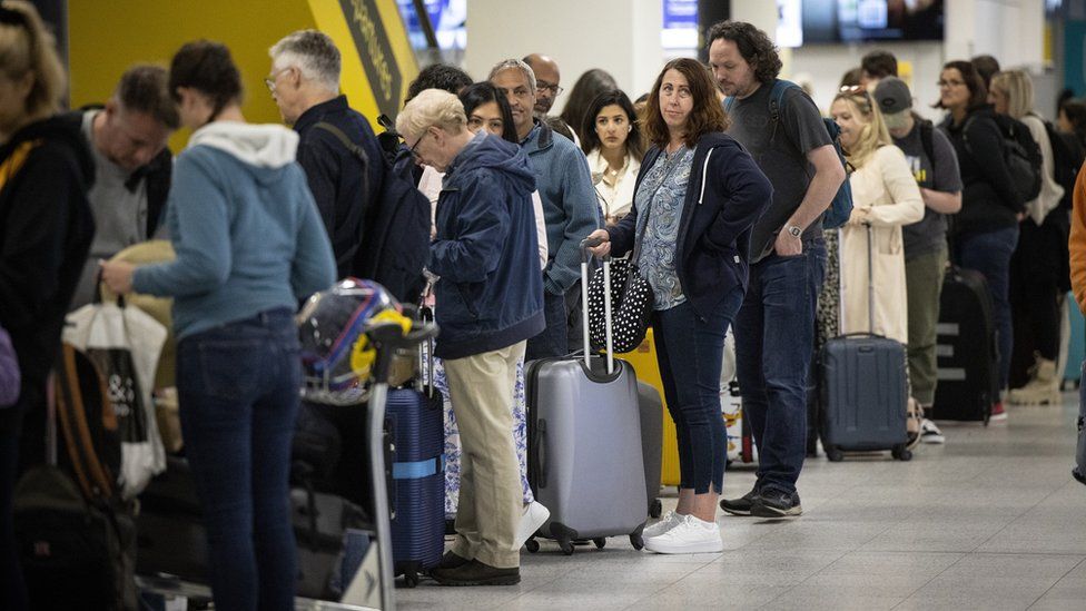 Travellers queue to check in for their flights at Gatwick Airport in London