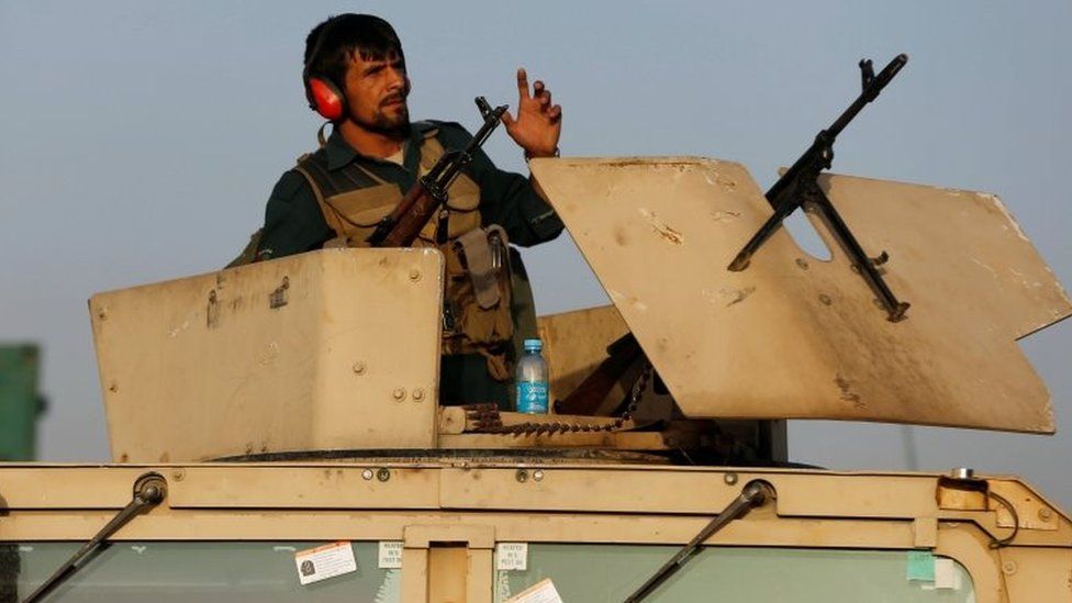 An armed Afghan policeman keeps near the site of a bomb blast in Kabul