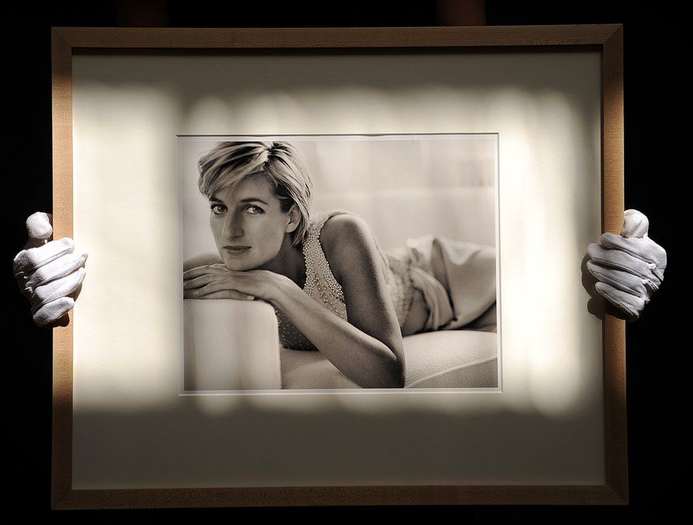 An employee holds a framed photograph of Diana, to be auctioned at Christie's