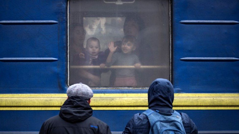 Children wave from a train at Kramatorsk central station as families flee the eastern city of Kramatorsk, in the Donbass region on April 4, 2022