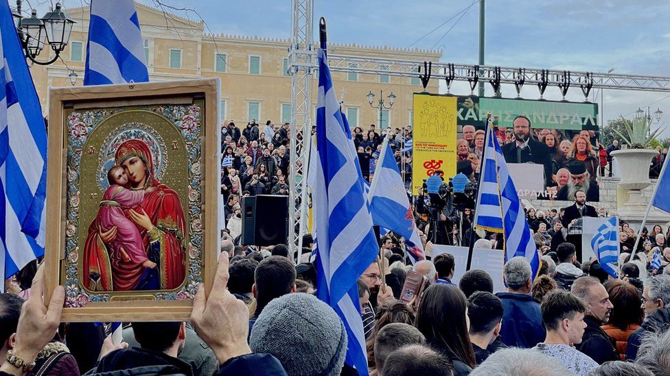 Protesters outside the Greek parliament hold up religious icons and wave Greek flags