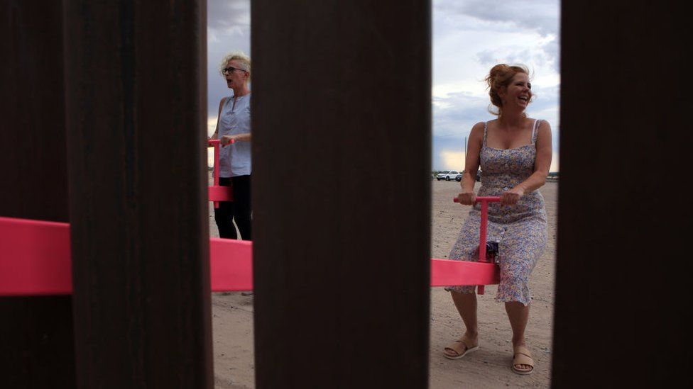 A woman plays on the installation on the Mexican border with the US