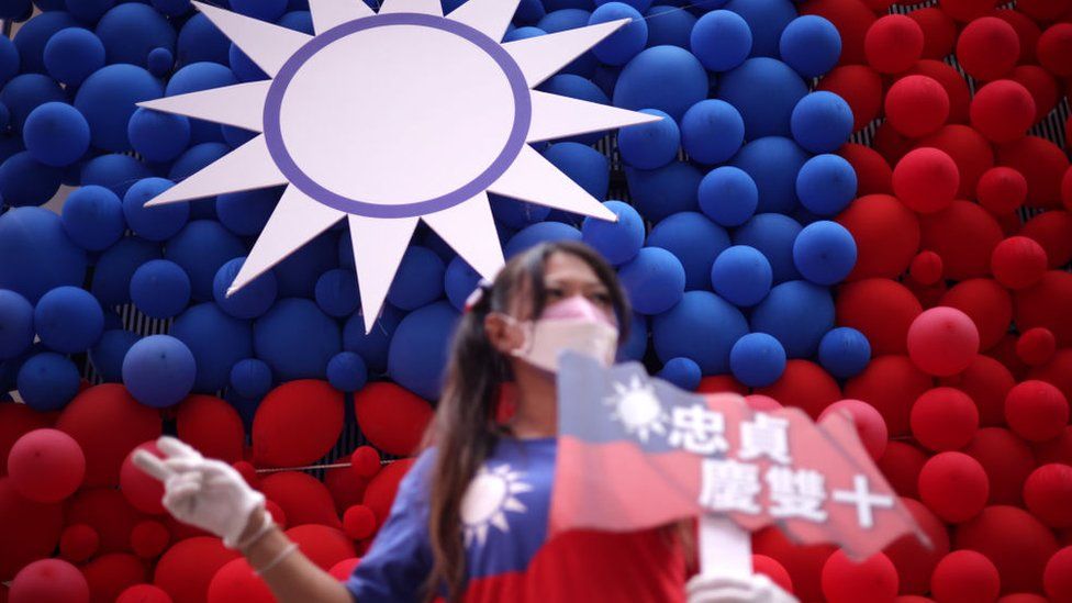 Женщина позирует для фотографий перед тайваньским флагом, сделанным из воздушных шаров, во время ярмарки, посвященной Национальному дню, в парке культуры «Новая деревня Чжунчжэнь», 10 октября 2023 г.