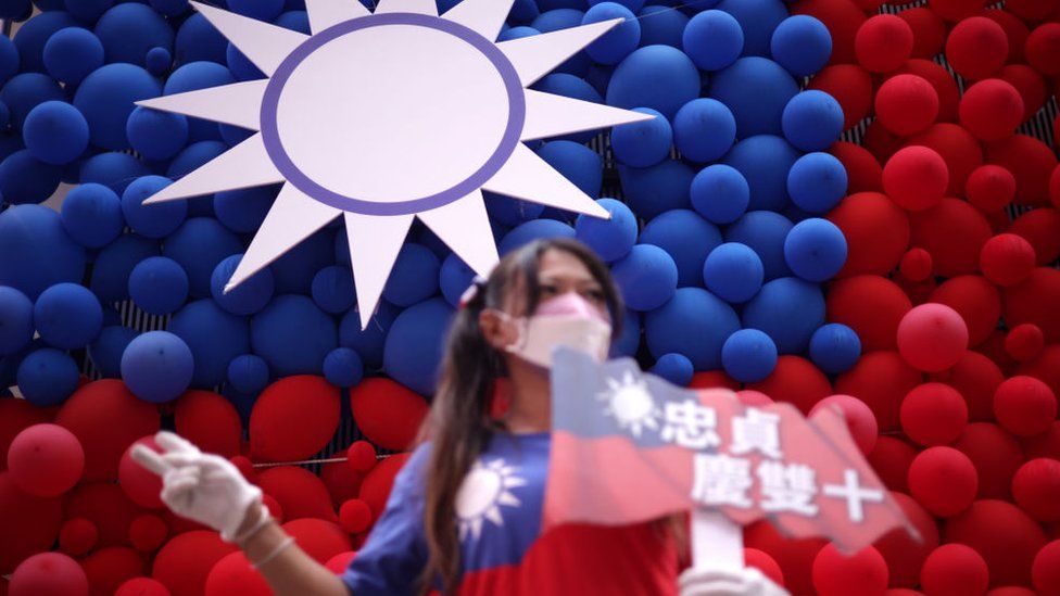 A woman poses for photos in front of a Taiwanese flag made with balloons during a fair to mark the National Day at Zhongzhen New Village Cultural Park on October 10, 2023