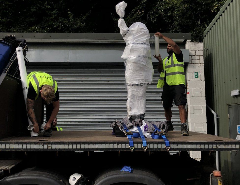Two men unloading the new statue from a lorry