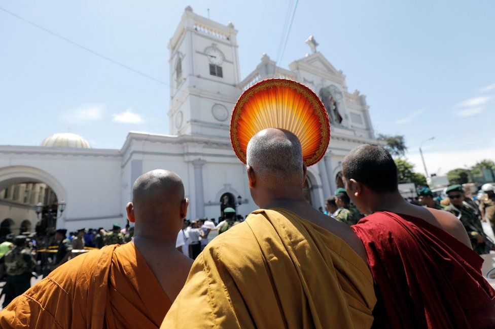 Buddhist monks stand in front of the St. Anthony's Shrine, Kochchikade