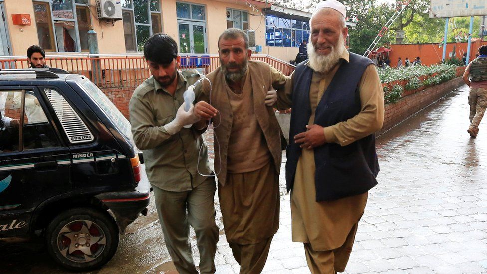 Men carry an injured person to a hospital after a bomb blast at a mosque, in Jalalabad