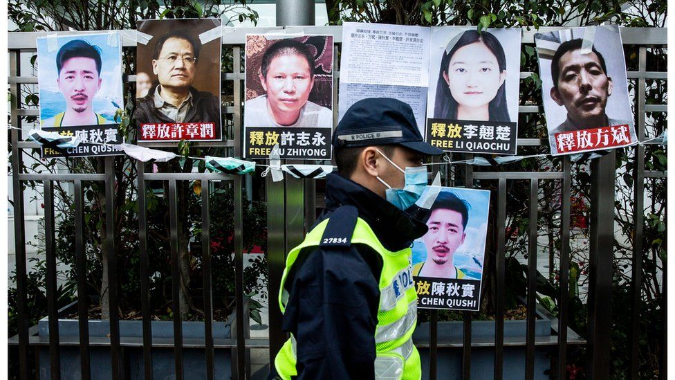 A Hong Kong police officer walks past images of detained activists