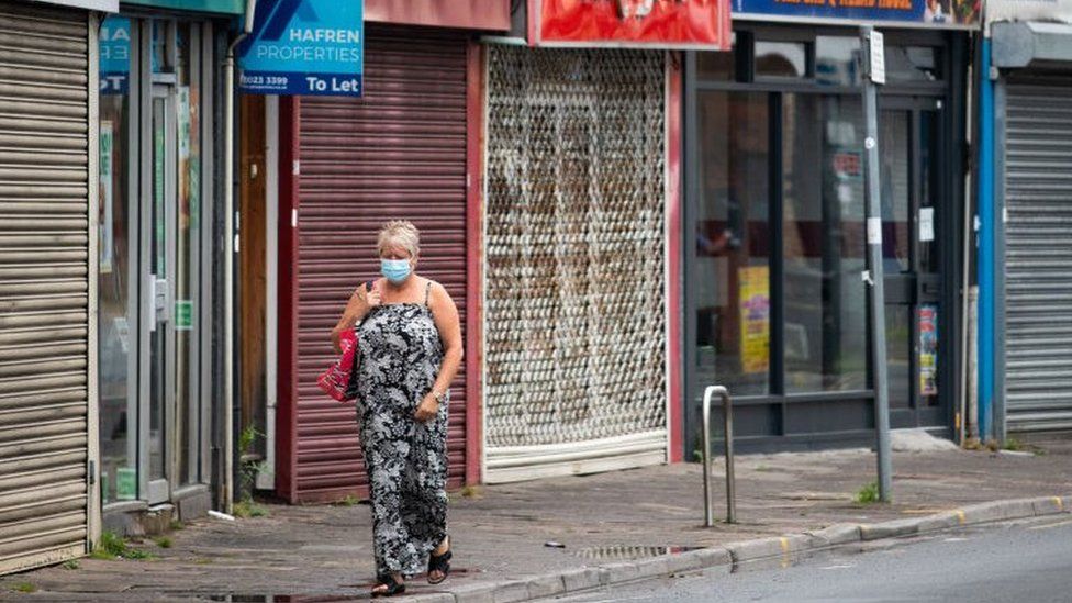 A woman walking along Cardiff street with closed shops behind