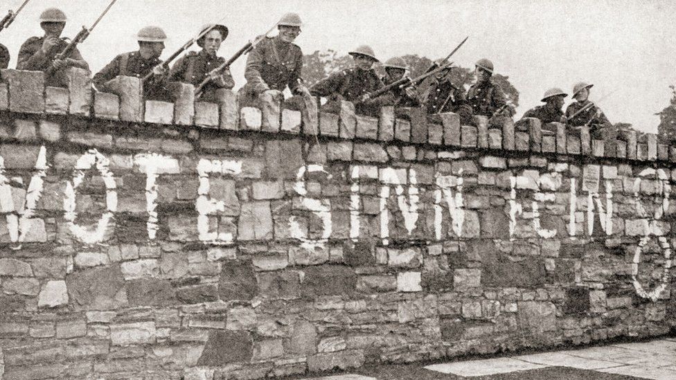 British troops guarding a wall which is plastered with a Sinn Fein advertisement during the Irish War of Independence aka Anglo-Irish War, in 1920.