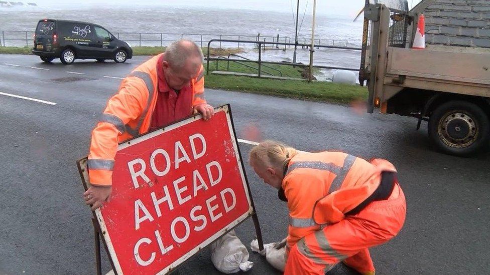 Workmen with road closed sign