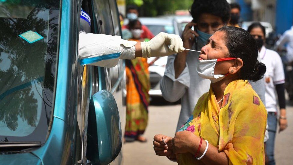 A health worker of Special Mobile Surveillance team in PPE coveralls collects a swab sample from a woman for Covid-19 rapid antigen test, at Model Town, on July 15, 2020 in New Delhi, India