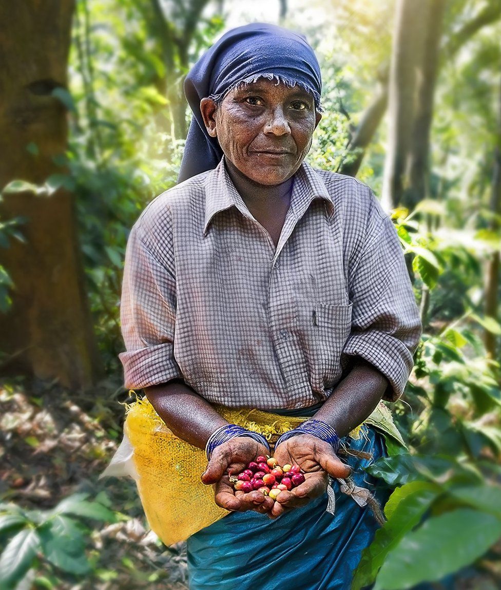 A woman holds out coffee beans