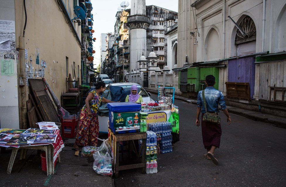 Thwarhairah exchanges money with her friend who sells newspapers next to her betel nut stand in downtown Yangon, Myanmar, November 14, 2015.