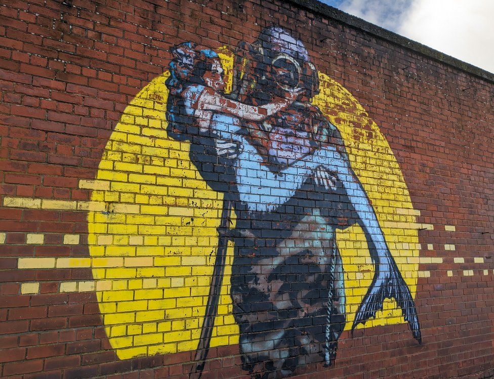 A painting a scuba diver carrying a mermaid on a wall on Dunbar Street in Belfast