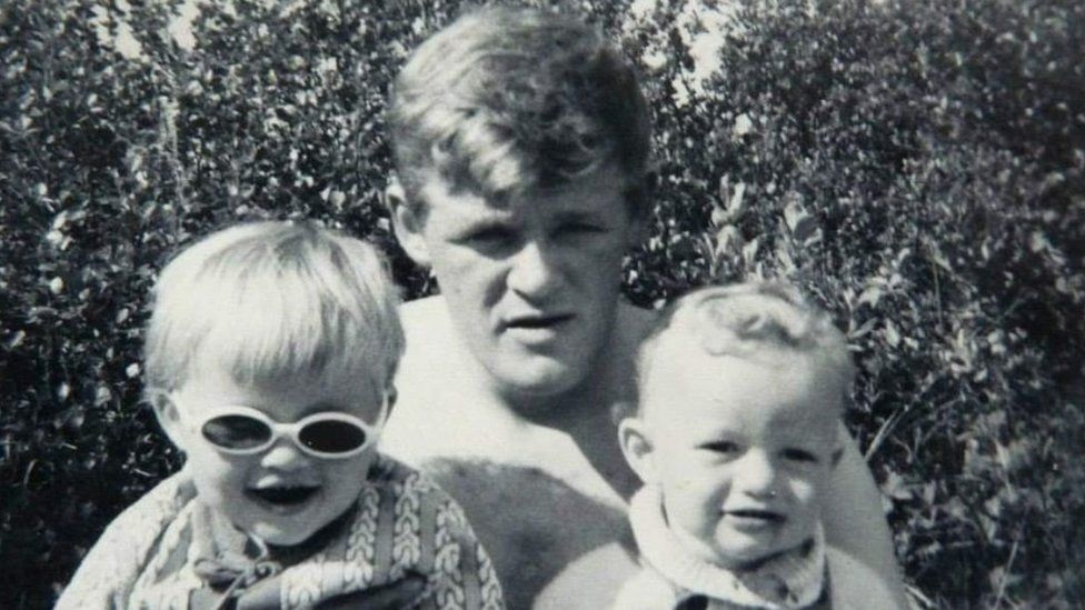 A black and white picture of a man and two young children
