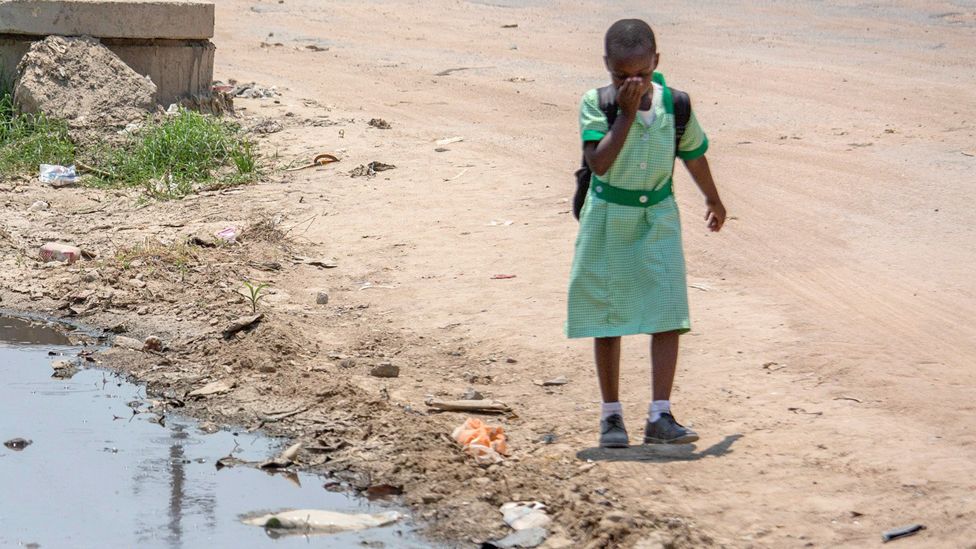 A schoolgirl walks past a pool of sewage in Chitungwiza, Zimbabwe - 9 October 2023