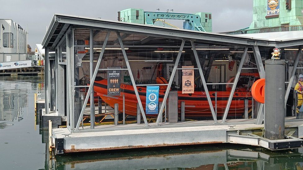 A glass-sided lifeboat house containing the orange inshore lifeboat at Poole Lifeboat Station