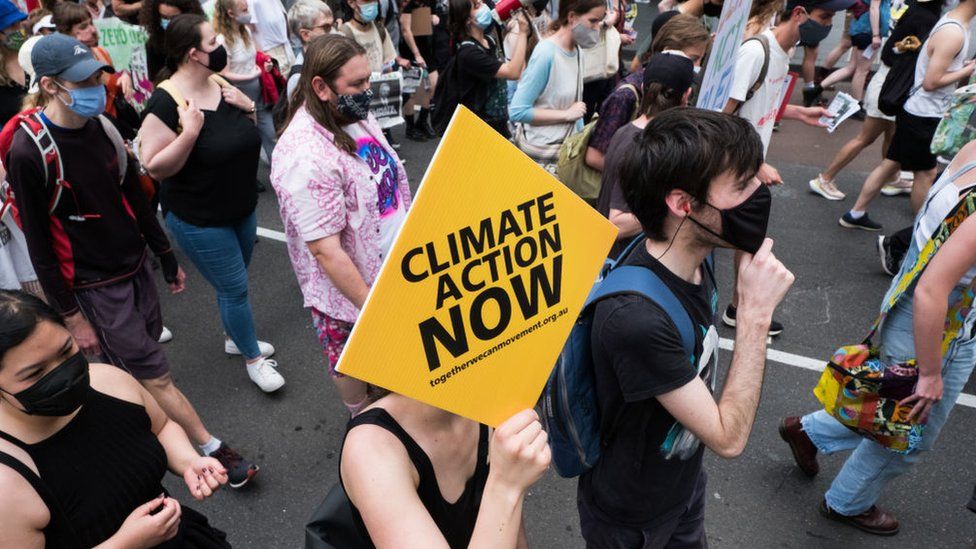 Протестующие против изменения климата маршируют и меняются, неся плакаты, 6 ноября 2021 года в Мельбурне, Австралия.