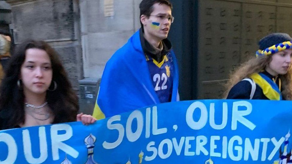 Tomas marches with other Ukraine supporters holding a banner that reads: Our soil, our sovereignty