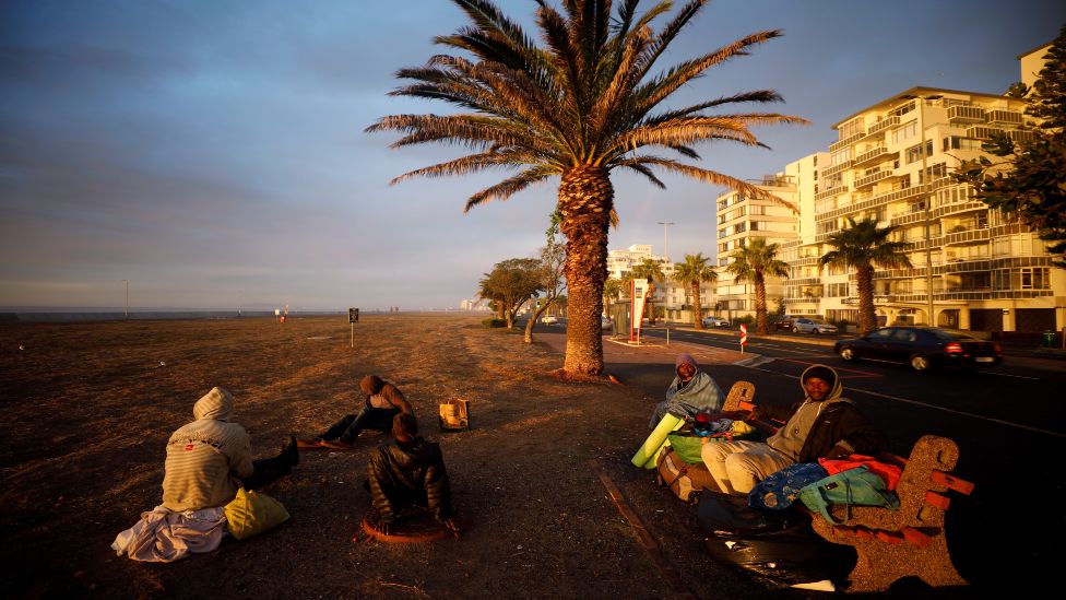 A group of homeless men take in the last of the days light before seeking a place to sleep in South Africa