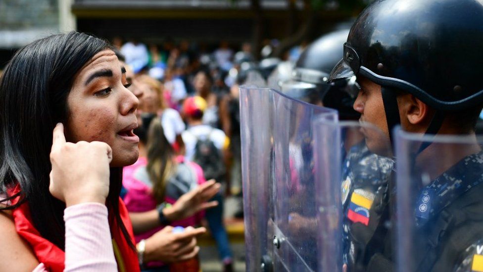 An opposition supporter speaks to police officers during a protest in Caracas on March 9, 2019