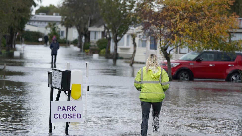 A person walks through flood water at Riverside Caravan Centre in Bognor Regis, West Sussex, after heavy rain the area