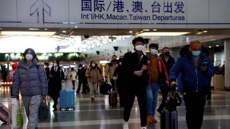 Travellers walk with their luggage at Beijing Capital International Airport