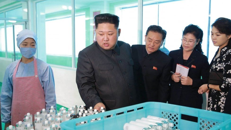 Kim Jong Un holds clear liquid samples in bottles at factory visit