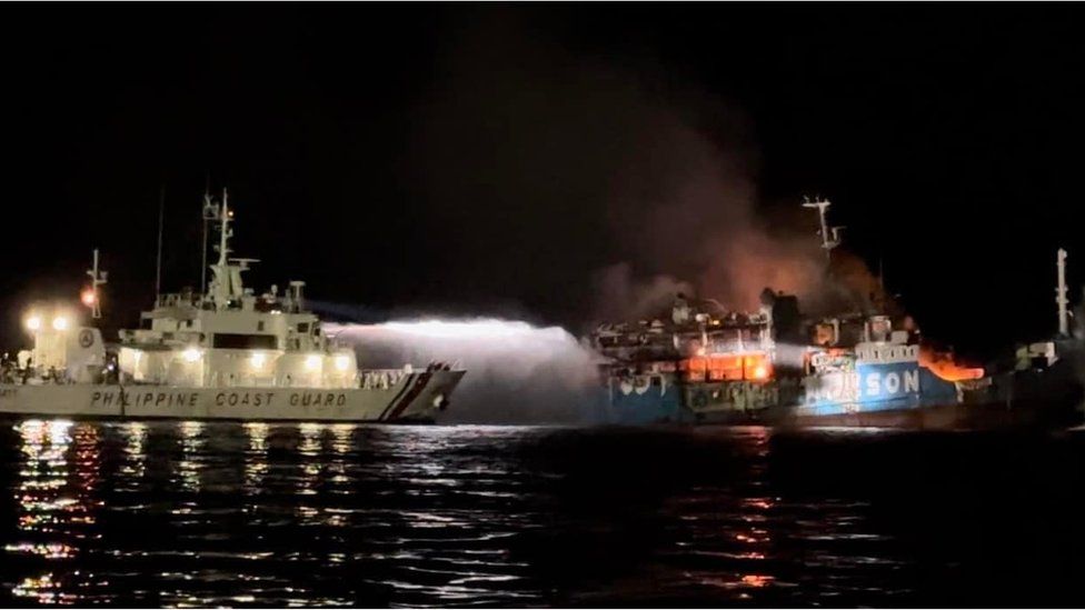 A Philippine Coast Guard vessel sprays water on a burning ship.