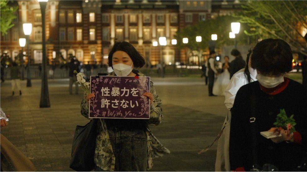 Женщина держит плакат с надписью «сексуальное насилие непростительно» на демонстрации цветов в центре Токио