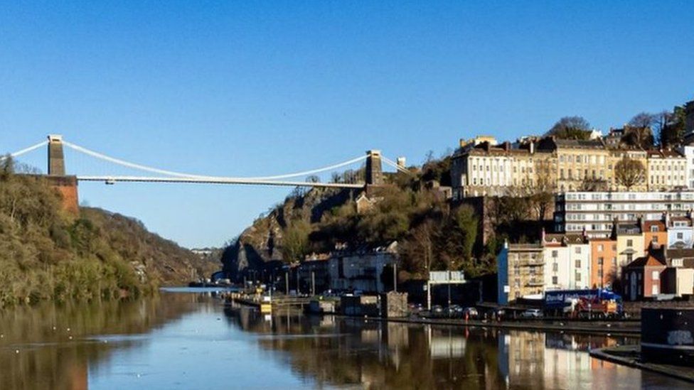 Clifton Suspension bridge from afar and a view over Clifton. The bridge is reflecting in the water