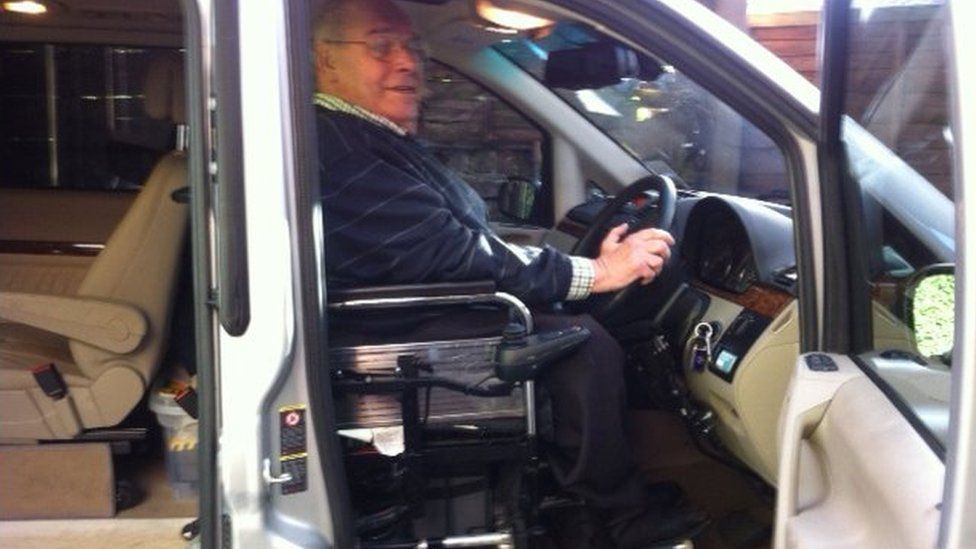 James sitting in his wheelchair at the steering wheel of his car
