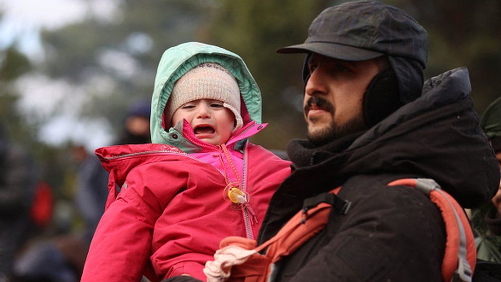 A man holds his child on the Poland-Belarus border