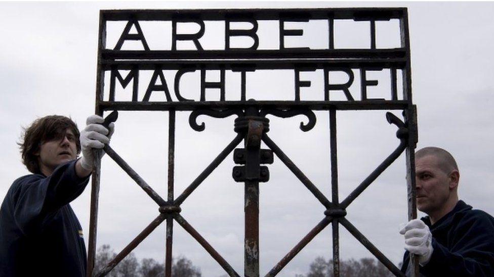 Transport company staff carry the "Arbeit macht frei" gate at the site of the former Nazi concentration camp in Dachau on 22 February, 2017.