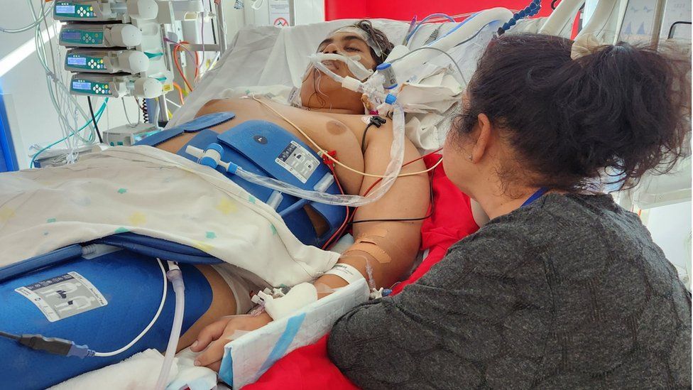 Cassius pictured in a hospital bed as his mother sits beside him