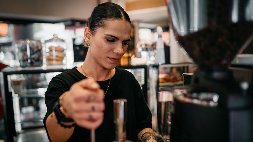 A person prepares coffee in a hospitality environment