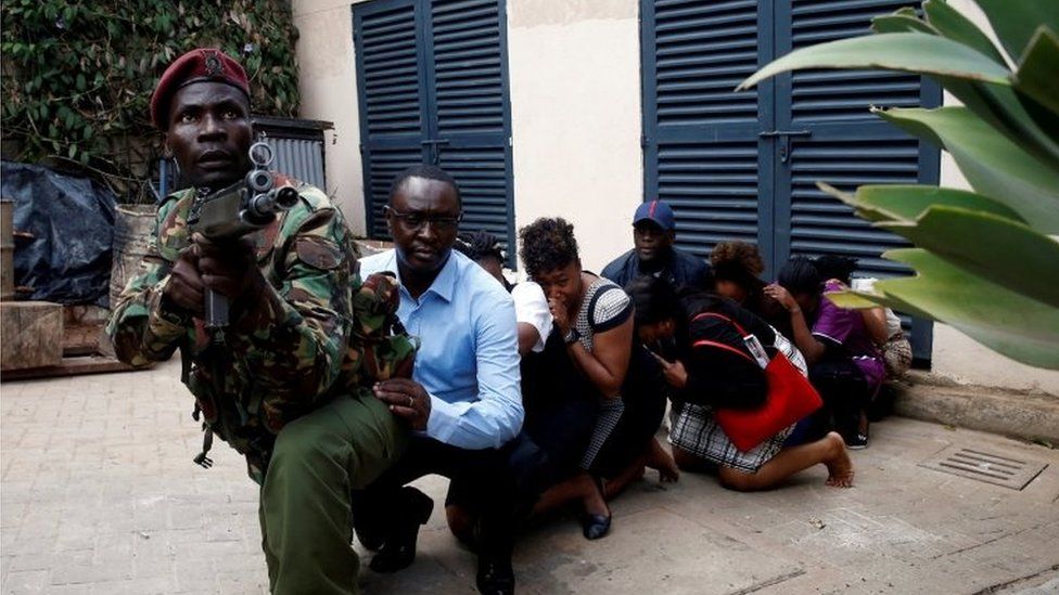 People are evacuated by a member of security forces at the scene where explosions and gunshots were heard at the Dusit hotel compound, in Nairobi, Kenya on 15 January 2019.