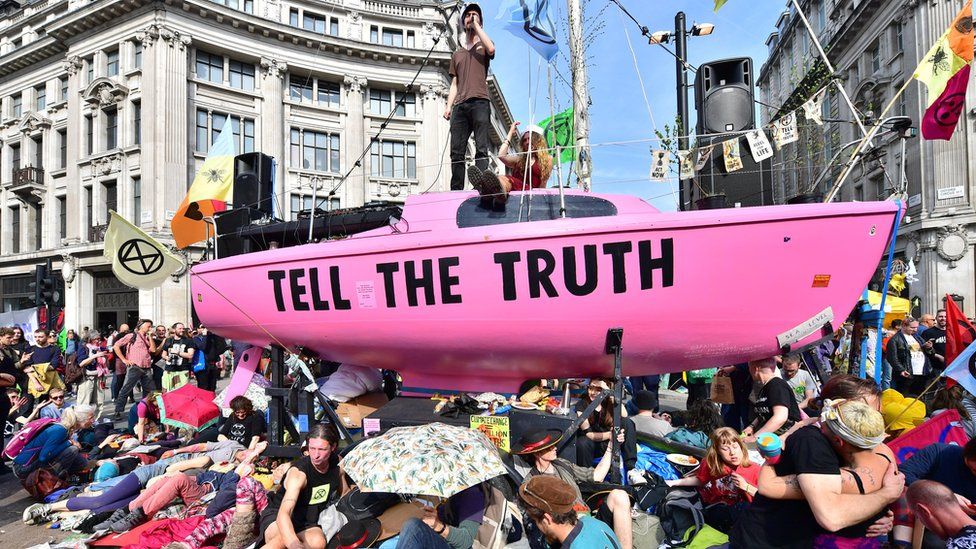 A man addresses crowds from the deck of a pink boat in Oxford Circus