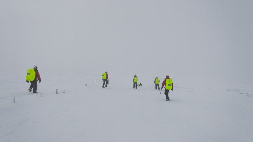 Mountain rescue teams in the snow wearing appropriate clothing