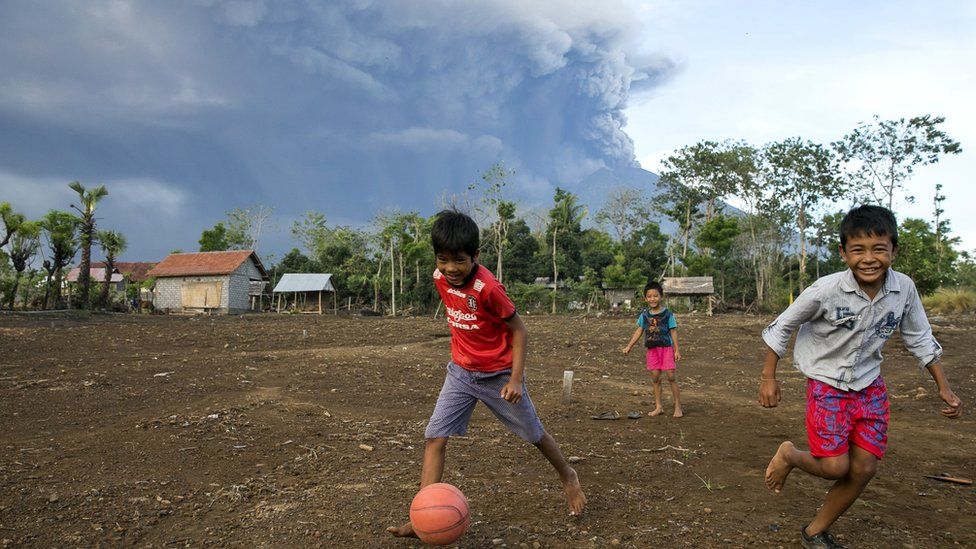 Balinese children play soccer as the Mount Agung volcano spews volcanic ash in Karangasem