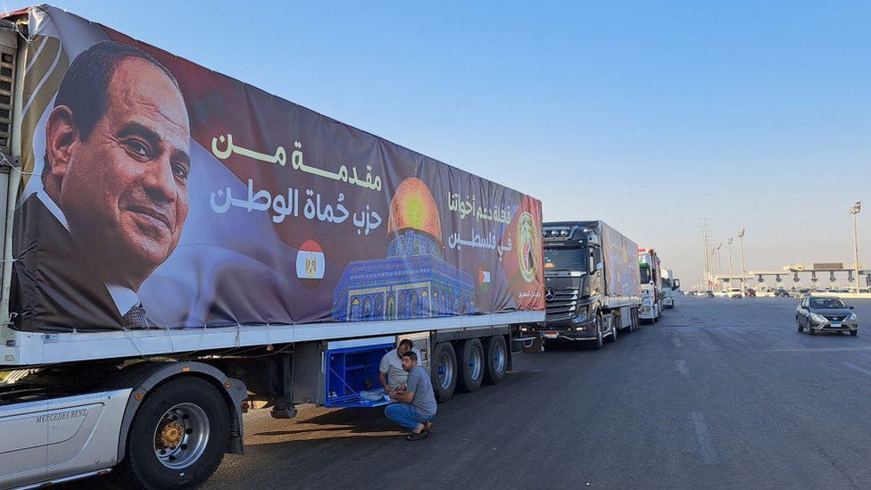 A convoy of trucks carrying aid supplies for Gaza from Egypt waits on the main Ismailia desert road, about 300 kms east of the Egyptian border with the Gaza Strip, on the way to the Rafah crossing on October 16, 2023. Portrait on the banner covering the truck shows Egypt's President Abdel Fattah al-Sisi, with the aid provided by an unaffiliated local political party. US Secretary of State Antony Blinken said while departing from Cair on October 15 the Rafah border crossing between Gaza and Egypt "will be open" for aid into the blockaded strip.