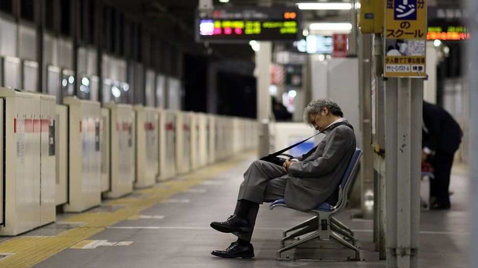 A businessman sleeping on a bench at a Tokyo train station