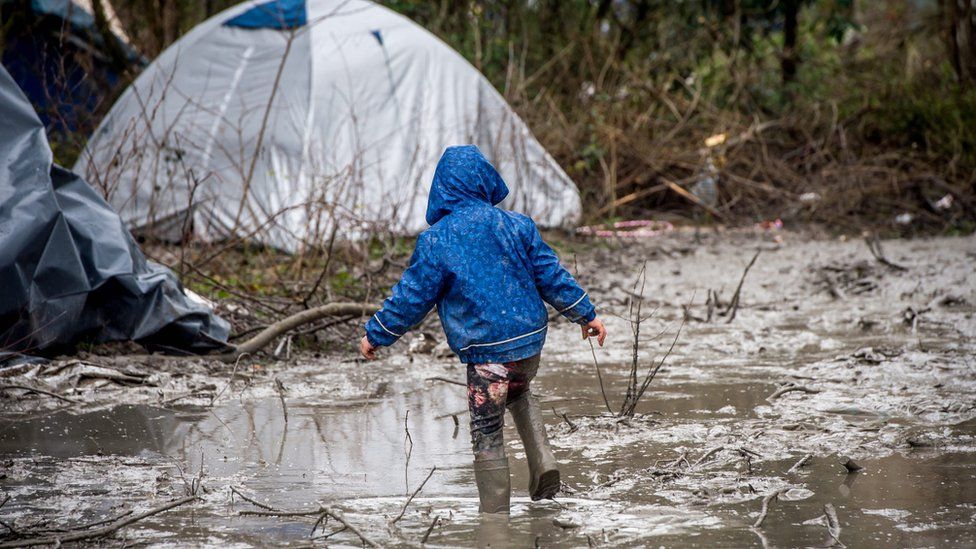 A refugee child walks in the mud in refugee camp in the coastal town of Grande-Synthe near Dunkirk, northern France, 10 January 2016